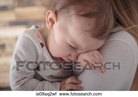 Toddler girl crying on mother's shoulder View Large Photo Image Stock Image - Toddler girl crying on mother's shoulder. Fotosearch
