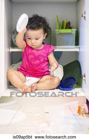 Toddler girl sitting in kitchen cupboard View Large Photo Image Stock Photograph - Toddler girl sitting in kitchen cupboard. Fotosearch