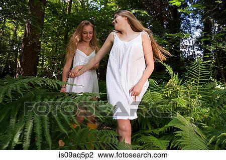 Stock Image - Two teenage girls wandering through forest. Fotosearch