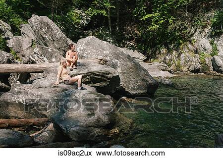 Stock Photo - Two women sitting by a swimming hole in woods. Fotosearch