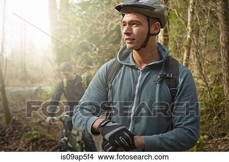 "Two young men in forest, riding mountain bikes" View Large Photo Image Picture - "Two young men in forest, riding mountain bikes". Fotosearch