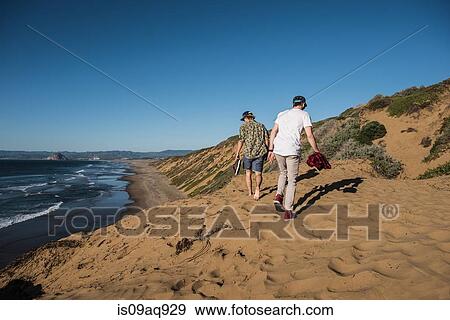 "Two young men walking along sand, rear view" View Large Photo Image Stock Photo - "Two young men walking along sand, rear view". Fotosearch
