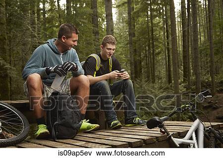 "Two young men with mountain bikes, in forest, taking a break" View Large Photo Image Stock Photo - "Two young men with mountain bikes, in forest, taking a break". Fotosearch