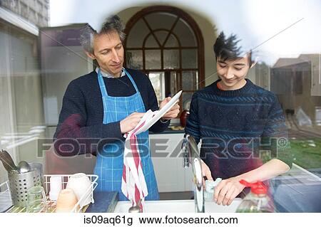 View through window of teenage boy and father washing up in kitchen View Large Photo Image Stock Image - View through window of teenage boy and father washing up in kitchen. Fotosearch