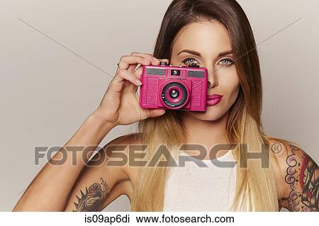 Stock Image - Woman holding up camera to eye. Fotosearch