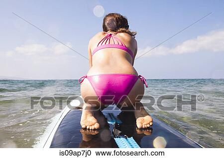 "Woman kneeling on surfboard, rear view" View Large Photo Image Stock Image - "Woman kneeling on surfboard, rear view". Fotosearch