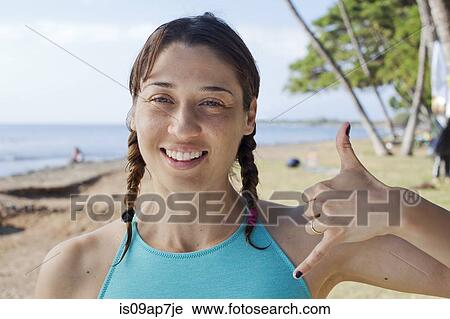 Stock Image - Woman making hand gesture on beach. Fotosearch