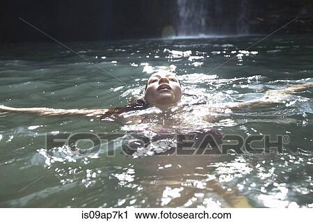 Stock Image - "Woman swimming, waterfall in background". Fotosearch