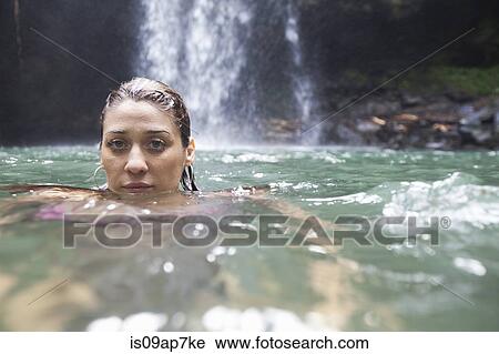 Stock Image - "Woman swimming, waterfall in background". Fotosearch