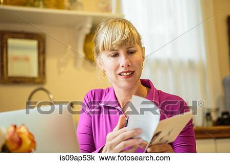 Woman working in kitchen table reading instruction booklet View Large Photo Image Stock Image - Woman working in kitchen table reading instruction booklet. Fotosearch