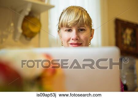 Woman working in kitchen table using laptop View Large Photo Image Stock Image - Woman working in kitchen table using laptop. Fotosearch