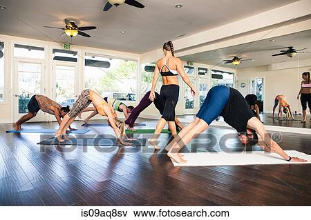 Yoga instructor in class with people in downward dog position View Large Photo Image Stock Photo - Yoga instructor in class with people in downward dog position. Fotosearch
