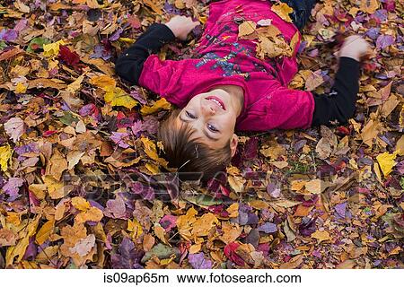 Picture - Young boy lying in autumn leaves. Fotosearch