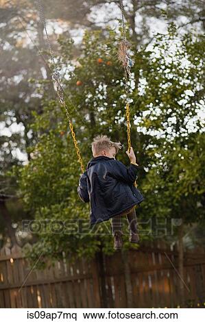 "Young boy swinging high on garden swing, rear view" View Large Photo Image Stock Photography - "Young boy swinging high on garden swing, rear view". Fotosearch