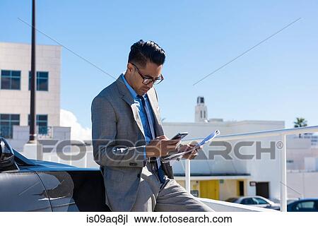 Young businessman in city car park reading smartphone texts View Large Photo Image Stock Image - Young businessman in city car park reading smartphone texts. Fotosearch