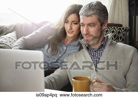 Young couple drinking coffee and looking at laptop View Large Photo Image Stock Photography - Young couple drinking coffee and looking at laptop. Fotosearch
