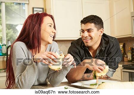 Young couple eating sandwiches at kitchen counter View Large Photo Image Picture - Young couple eating sandwiches at kitchen counter. Fotosearch