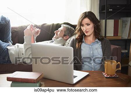 Young couple in sitting room using laptop and digital tablet View Large Photo Image Stock Photograph - Young couple in sitting room using laptop and digital tablet. Fotosearch
