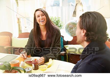 Young couple laughing at breakfast table View Large Photo Image Stock Photo - Young couple laughing at breakfast table. Fotosearch