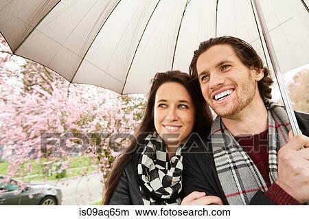 Young couple strolling in park with umbrella View Large Photo Image Picture - Young couple strolling in park with umbrella. Fotosearch