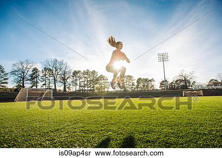 Young female athlete doing jump training on sports field View Large Photo Image Stock Photography - Young female athlete doing jump training on sports field. Fotosearch
