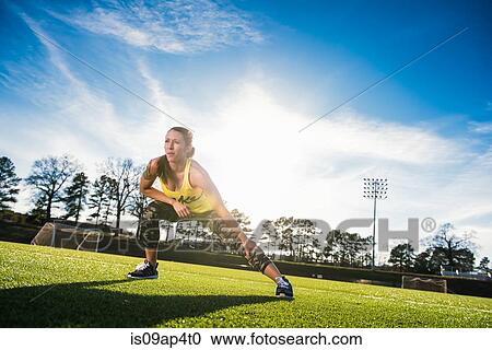 Young female athlete doing stretch exercises on sports field View Large Photo Image Stock Image - Young female athlete doing stretch exercises on sports field. Fotosearch