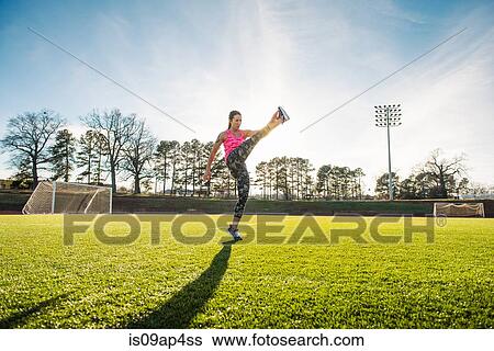 Stock Photograph - Young female athlete touching toes on sports field. Fotosearch