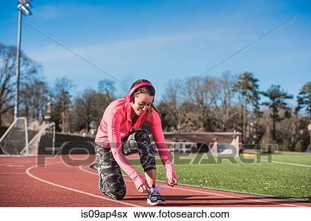 Young female athlete tying trainer laces on track View Large Photo Image Stock Photo - Young female athlete tying trainer laces on track. Fotosearch