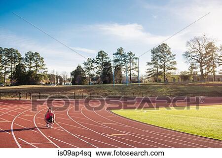 Stock Photography - Young female athlete tying trainer laces on race track. Fotosearch
