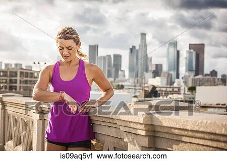 "Young female runner checking wristwatch on bridge, Los Angeles, California, USA" View Large Photo Image Stock Image - "Young female runner checking wristwatch on bridge, Los Angeles, California, USA". Fotosearch