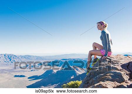 Stock Photo - "Young female trail runner gazing from rock on Pacific Crest Trail, Pine Valley, California, USA". Fotosearch