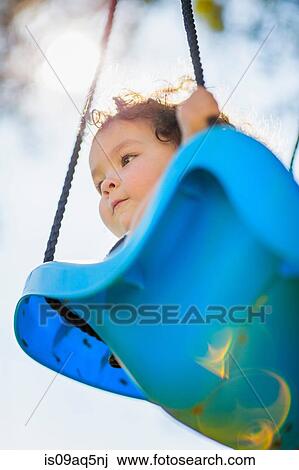 "Young girl on playground swing, low angle view" View Large Photo Image Stock Image - "Young girl on playground swing, low angle view". Fotosearch
