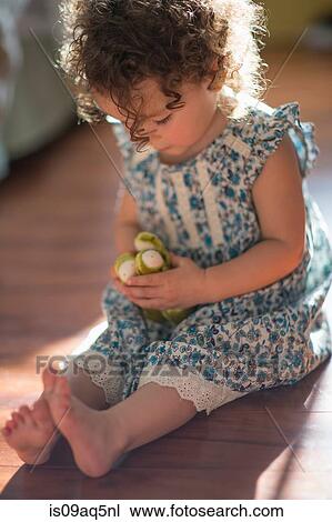 "Young girl, sitting on floor, playing with toy" View Large Photo Image Stock Image - "Young girl, sitting on floor, playing with toy". Fotosearch