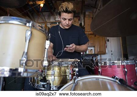 Young male drummer in basement reading smartphone texts View Large Photo Image Stock Photo - Young male drummer in basement reading smartphone texts. Fotosearch