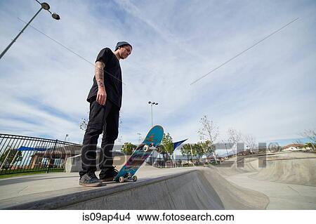 Young male skateboarder standing on edge of skateboard park View Large Photo Image Picture - Young male skateboarder standing on edge of skateboard park. Fotosearch