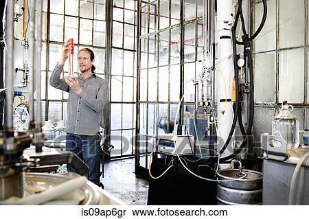 Young male vodka distiller measuring liquid in cylinder in distillery workshop View Large Photo Image Stock Photography - Young male vodka distiller measuring liquid in cylinder in distillery workshop. Fotosearch