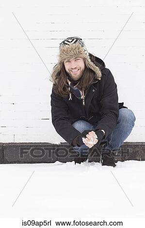 Young man crouching snow covered street making snowball View Large Photo Image Stock Image - Young man crouching snow covered street making snowball. Fotosearch