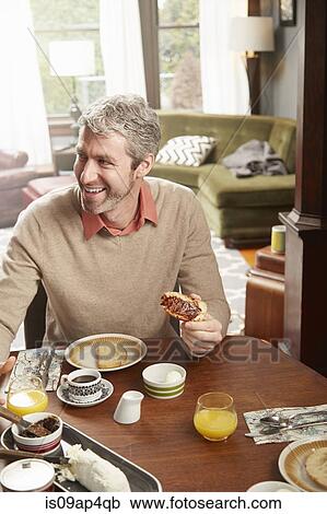 Young man eating breakfast in kitchen View Large Photo Image Stock Image - Young man eating breakfast in kitchen. Fotosearch