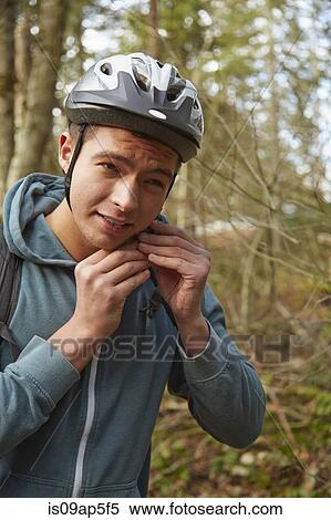 Young man in forest securing bicycle helmet View Large Photo Image Stock Photography - Young man in forest securing bicycle helmet. Fotosearch
