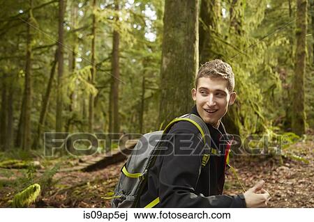 Young man in forest wearing backpack View Large Photo Image Stock Image - Young man in forest wearing backpack. Fotosearch