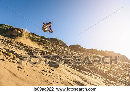 "Young man jumping down sandy hill, in mid air" View Large Photo Image Stock Image - "Young man jumping down sandy hill, in mid air". Fotosearch