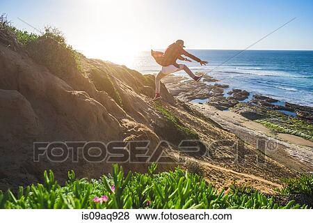 "Young man jumping down sandy hill, in mid air" View Large Photo Image Stock Photo - "Young man jumping down sandy hill, in mid air". Fotosearch