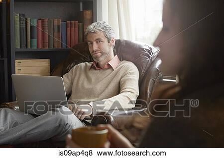 Young man looking sideways at girlfriend in sitting room View Large Photo Image Stock Photo - Young man looking sideways at girlfriend in sitting room. Fotosearch