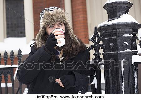 Young man looking sideways from snow covered street drinking takeaway coffee View Large Photo Image Picture - Young man looking sideways from snow covered street drinking takeaway coffee. Fotosearch