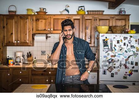 Young man on cell phone in kitchen View Large Photo Image Stock Photo - Young man on cell phone in kitchen. Fotosearch