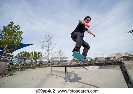 Stock Image - Young man skateboarding on top of railing. Fotosearch