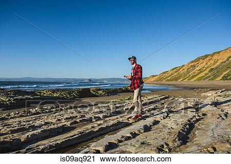Young man standing on beach looking at ocean View Large Photo Image Stock Image - Young man standing on beach looking at ocean. Fotosearch
