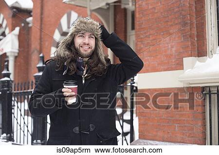 Young man strolling along street drinking takeaway coffee View Large Photo Image Picture - Young man strolling along street drinking takeaway coffee. Fotosearch