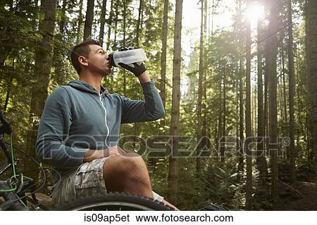 "Young man with mountain bike in forest, taking drink from water bottle" View Large Photo Image Stock Photograph - "Young man with mountain bike in forest, taking drink from water bottle". Fotosearch