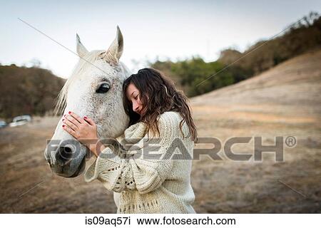 Young woman leaning against and petting white horse in field View Large Photo Image Stock Image - Young woman leaning against and petting white horse in field. Fotosearch